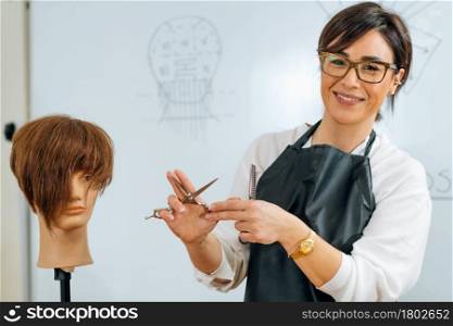 Hand of a hairdresser holding hairdressing scissors, explaining students haircutting techniques to students. Hand of a Hairdresser Holding Hairdressing Scissors, Explaining Haircutting Techniques to Students