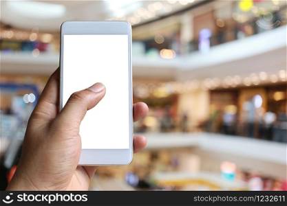 Hand of a man holding smartphone device in the Shopping mall background and have white copy space on screen.