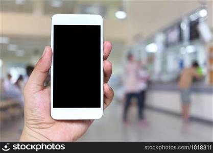 Hand of a man holding smartphone device on blur hospital background and have clipping paths for design.