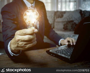 hand of a man with a light bulb And there is a gear icon in it and he is using a notebook computer, ideas inspired by online technology, innovative ideas.
