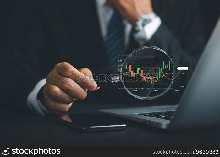 Hand of a professional trader holds a magnifier glass, studying the technical graph of the stock market chart. Business investment concept for financial analysis and trading success.