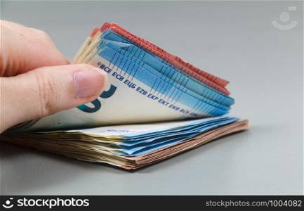 Hand of a woman counting a heap of euros banknotes