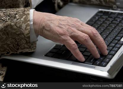 hand of a woman older then 80 , working on a mobile laptop