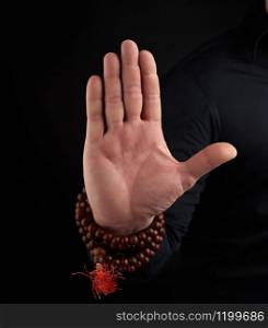 hand of an adult male shows mudra on a dark background, close up