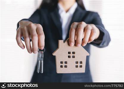 hand of Asian business woman are holding key and model houses.
