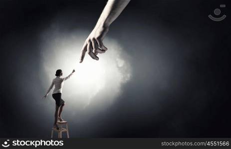 Hand of assistance and help. Young woman standing on chair and reaching hand to get help