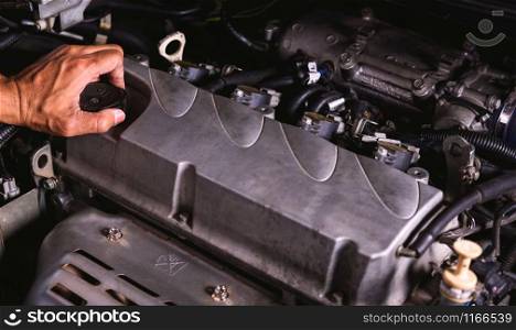 Hand of auto mechanic technician service engine and open the engine oil lid on car in garage