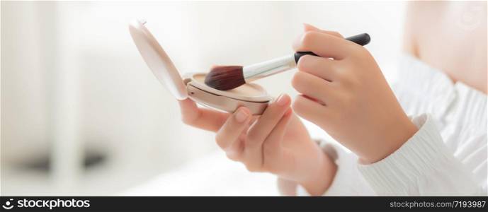 hand of beauty young asian woman with face looking mirror applying makeup with brush cheek in the bedroom, beautiful girl holding blusher facial, skin care and cosmetic concept, banner website.