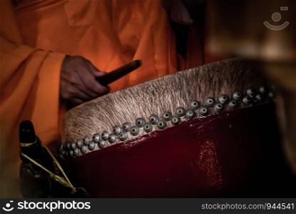 Hand of Buddhist monk striking a drum to pay respect for Buddhism pray, religion.