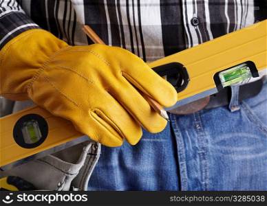 hand of builder with yellow protective glove and level, selective focus, studio lighting