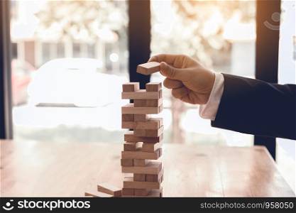 Hand of businessman playing wood blocks stacks game with planning strategy of project management.