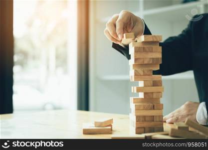 Hand of businessman playing wood blocks stacks game with planning strategy of project management.