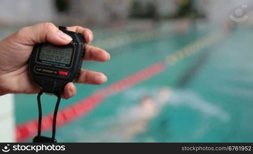 hand of coach with a stopwatch during competitions in the swimming pool