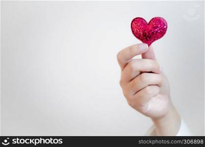 hand of female holding mini red heart with copy space background.
