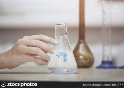 Hand of laboratory technician holding flask with chemical