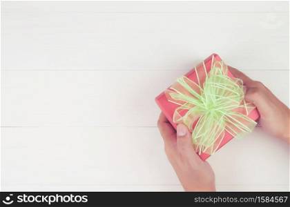 Hand of man holding gift giving on wooden table in Christmas day or holiday, present box for anniversary or birthday or celebration with copy space, celebrate and festive, top view, flat lay.
