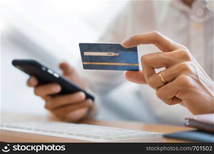 Hand of man in casual shirt paying with credit card and using smart phone for online shopping making orders via the Internet using mobile bank application, Online payment