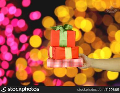 Hand of man with a red gift box on bokeh background for design in your work concept.