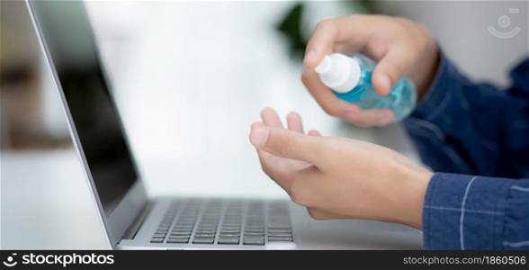 Hand of man work from home with alcohol gel or sanitizer for cleaning hand and protect coronavirus or covid-19, new normal, quarantine and social distancing, businessman using laptop computer.