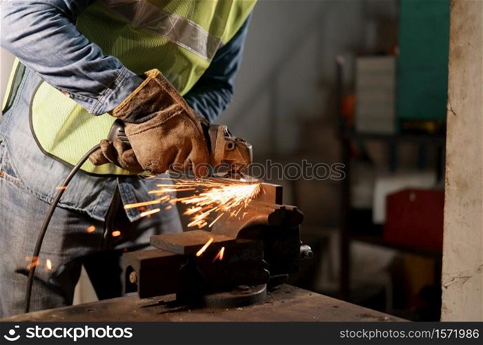 Hand of man work wearing gloves while Grinding metal and orange flying sparks in the factory