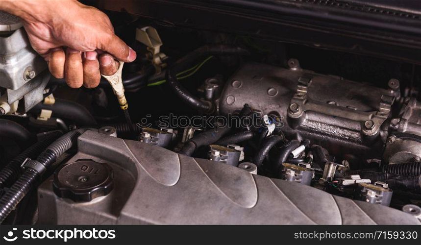 Hand of Mechanic technician service check level motor oil engine in garage
