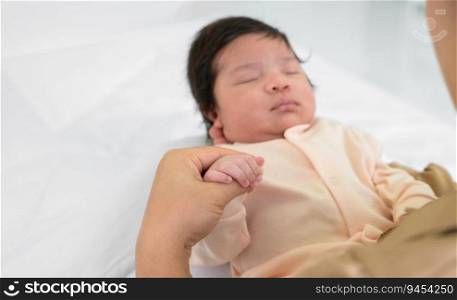 Hand of mother holding finger of newborn hand. Adorable infant girl 1 month sleeping on mom arm at home. Care, love and mothers day concept.