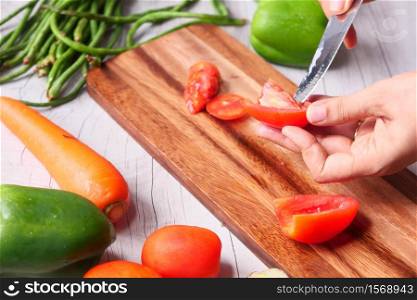 Hand Of Person Cutting Tomatoes On Chopping Board.. Hand Of Person Cutting Tomatoes On Chopping Board
