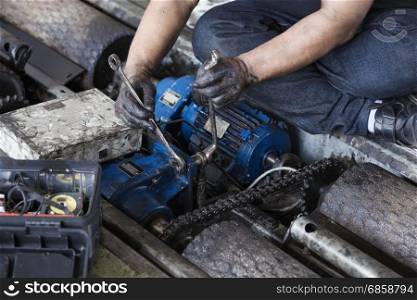 Hand of repairman holding a wrench and tighten and during maintenance work of electric motor