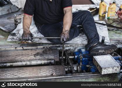 Hand of repairman holding a wrench and tighten and during maintenance work of machine