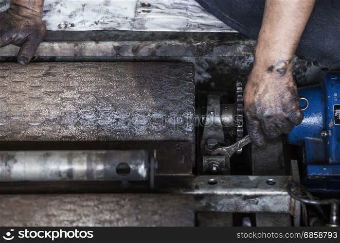 Hand of repairman holding a wrench and tighten and during maintenance work of machine