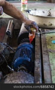 Hand of repairman oiling gear and during maintenance work of electric motor