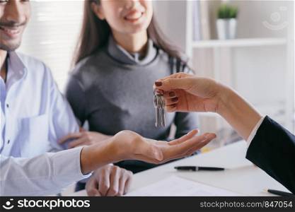 hand of Salespeople give keys to couples who are customer. Men are doing business in the office, business concept.