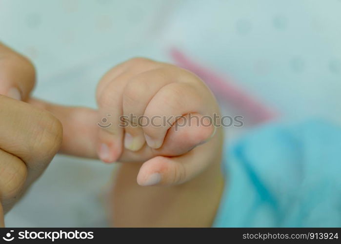 Hand of sleeping baby in the hand of mother close up on the bed, New family and baby protection from mom concept