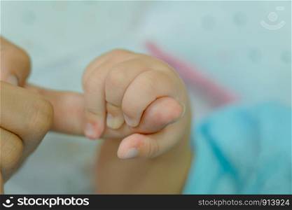 Hand of sleeping baby in the hand of mother close up on the bed, New family and baby protection from mom concept