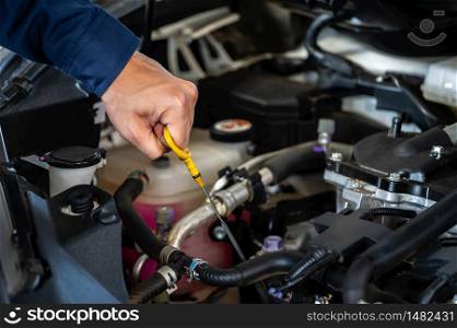 hand of technician checking the oil level on dipstick in a car engine