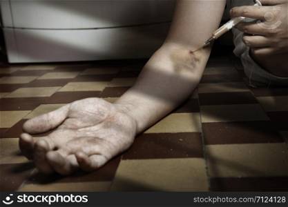 Hand of the narcotist with syringe on the floor. Artistic colors added