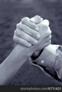 Hand of woman and hand of man is clasped together in symbolic strength of unity