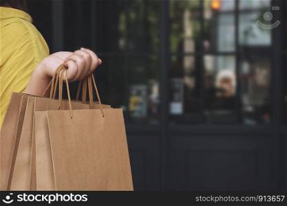 Hand of woman holding paper bags enjoy with shopping in the mall.