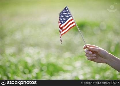 Hand of woman holding US flag in a grassland