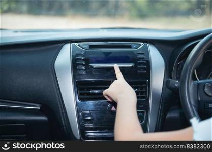 Hand of woman turning on car air condition system,Button on dashboard in car panel,Auto car air condition Car dashboard. Radio closeup. Woman sets up radio.