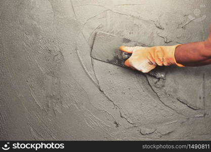 hand of worker plastering cement at wall for building house