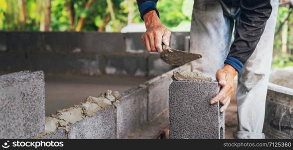 hand of worker plastering cement on brick wall at construction site