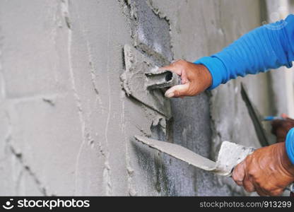 hand of worker plastering cement on wall