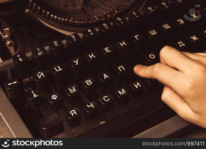 hand on a typewriter on a wooden background.. hand on a typewriter on a wooden background