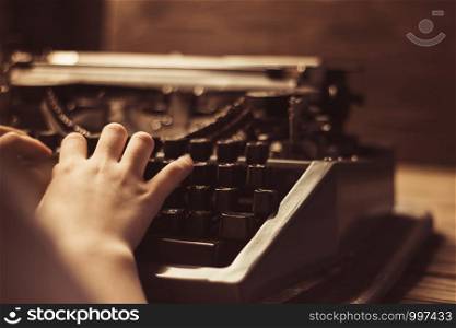 hand on a typewriter on a wooden background. Retro style.. hand on a typewriter on a wooden background. Retro style