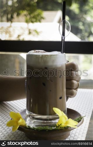 Hand on iced coffee at balcony wooden table, stock photo