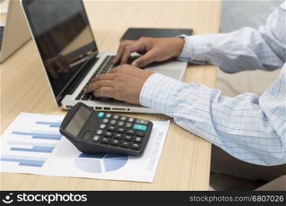 hand on laptop computer with digital tablet, calculator and document for use as working concept