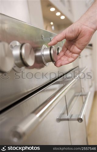 Hand on stove dial in kitchen