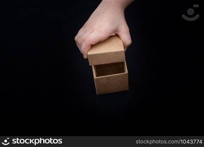 Hand opening a brown cardboard box on black backgrounds