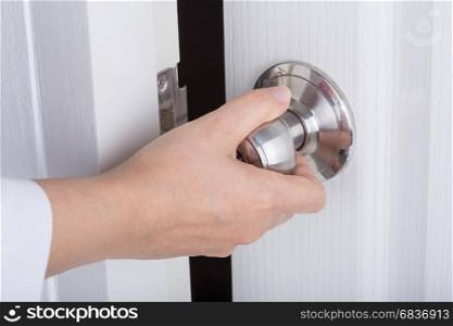 Hand opening door knob on the white door